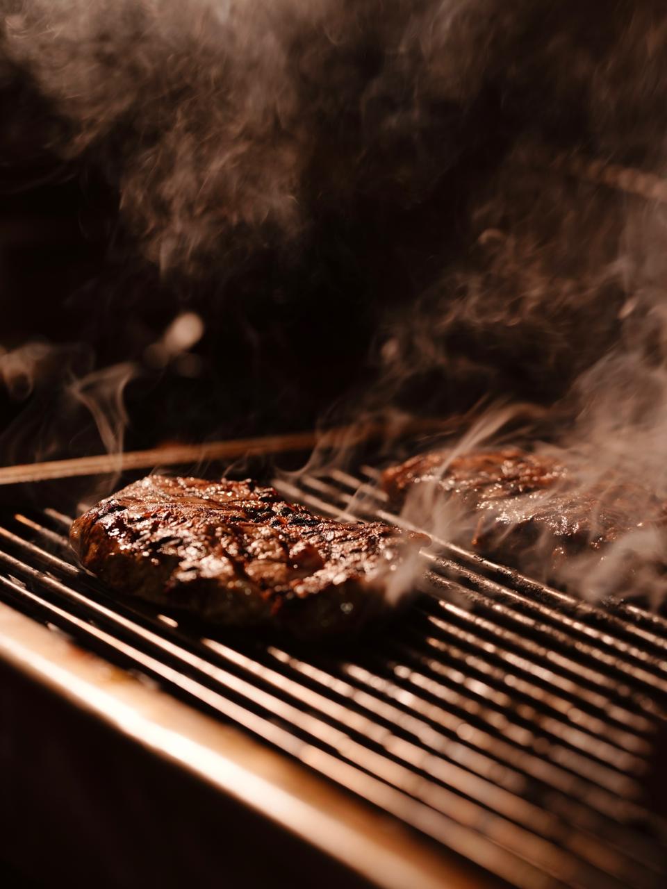 Steaks cooking over the grill at Corner Pizza and Grill